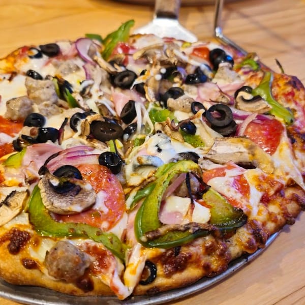 Halftime Pizza's supreme pizza, loaded with pepperoni, sausage, olives, mushrooms, onions, and peppers.