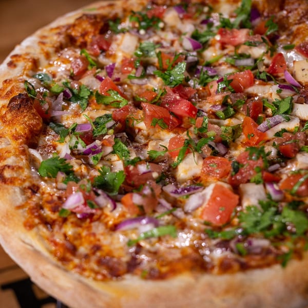 Halftime Pizza's chicken pizza, topped with diced tomatoes, red onions, and fresh cilantro.