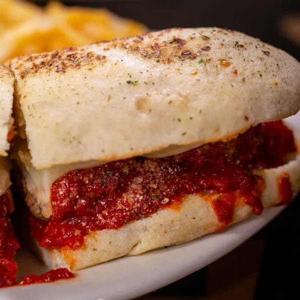 A close-up of a Halftime Pizza meatball sub with marinara sauce and melted cheese.