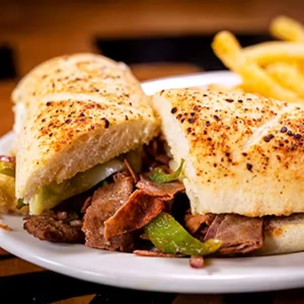 Halftime Pizza's steak and cheese sub with green peppers and onions, served with fries.