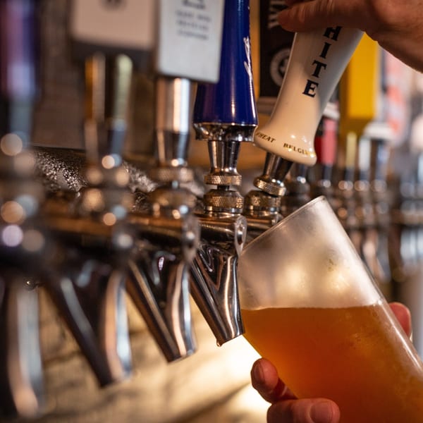 Hand holding a glass of beer being filled from a tap at Halftime Pizza.