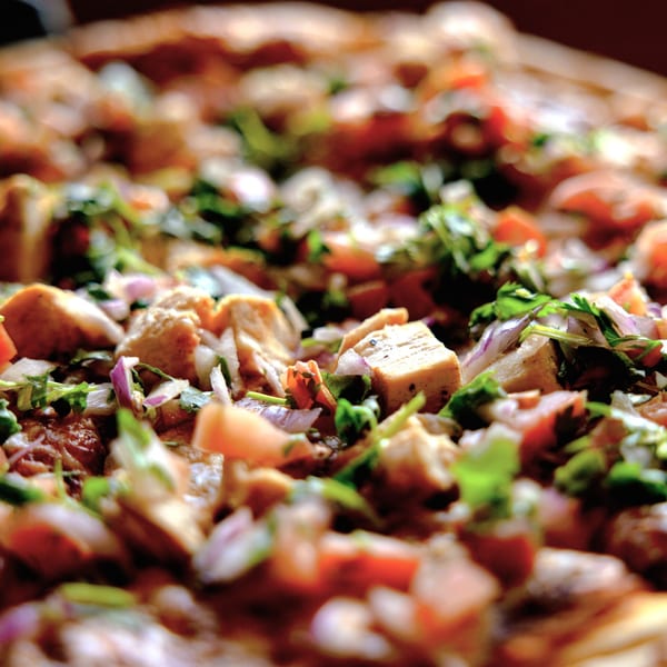 Close-up of Halftime Pizza's chicken pizza, topped with diced chicken, red onions, and cilantro.