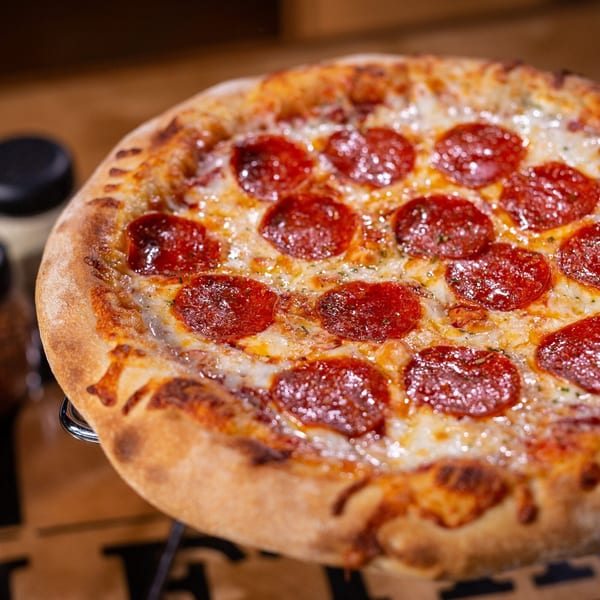 Close-up of a Halftime Pizza pepperoni pizza with melted cheese and a golden crust.